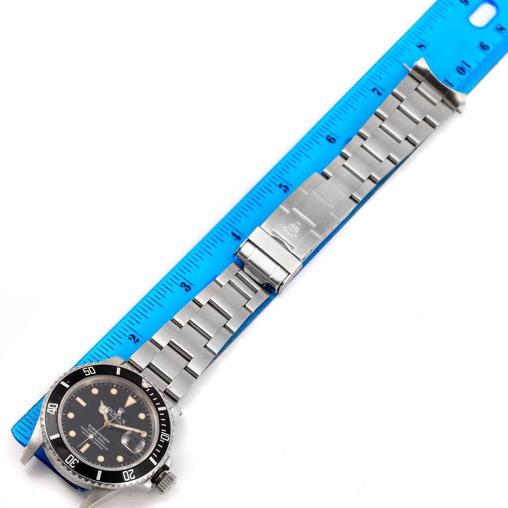 The image shows a Rolex Vintage Collection 16800 Men's Stainless Steel Black Dial 16800 Men's Stainless Steel Black Dial watch laid flat next to a blue ruler, highlighting its stainless steel band and face.