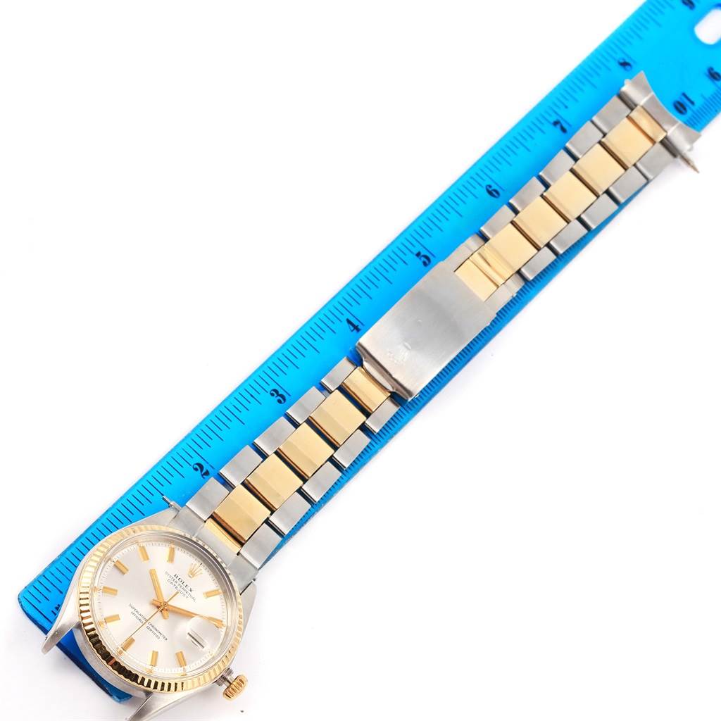 This image shows a Rolex Vintage Collection 1601 Men's Stainless Steel Silver Dial 1601 Men's Stainless Steel Silver Dial watch and its metal and gold link bracelet, positioned next to a blue ruler.