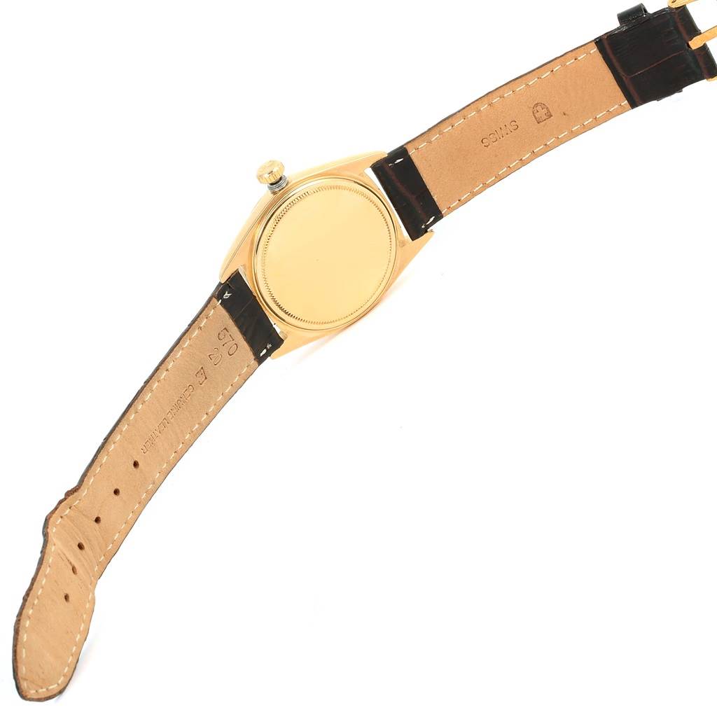 The image shows the back view of a Rolex Vintage Collection 1601 Men's Yellow Gold Champagne Dial 1601 Men's Yellow Gold Champagne Dial watch, displaying its leather strap and golden caseback.