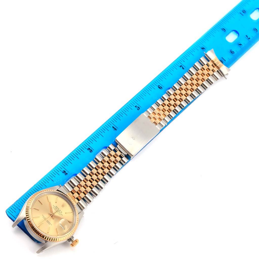 This image shows a Rolex Vintage Collection 16013 Men's Stainless Steel Champagne Dial 16013 Men's Stainless Steel Champagne Dial watch laid flat next to a blue ruler, highlighting its dial, bracelet, and clasp.