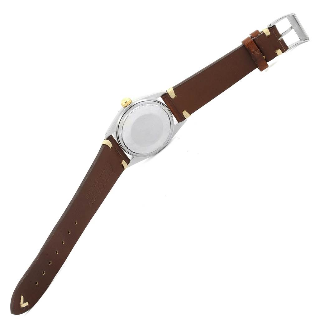 The image shows the back and strap of a Vintage Collection model by Rolex, with a brown leather strap and a silver case-back.