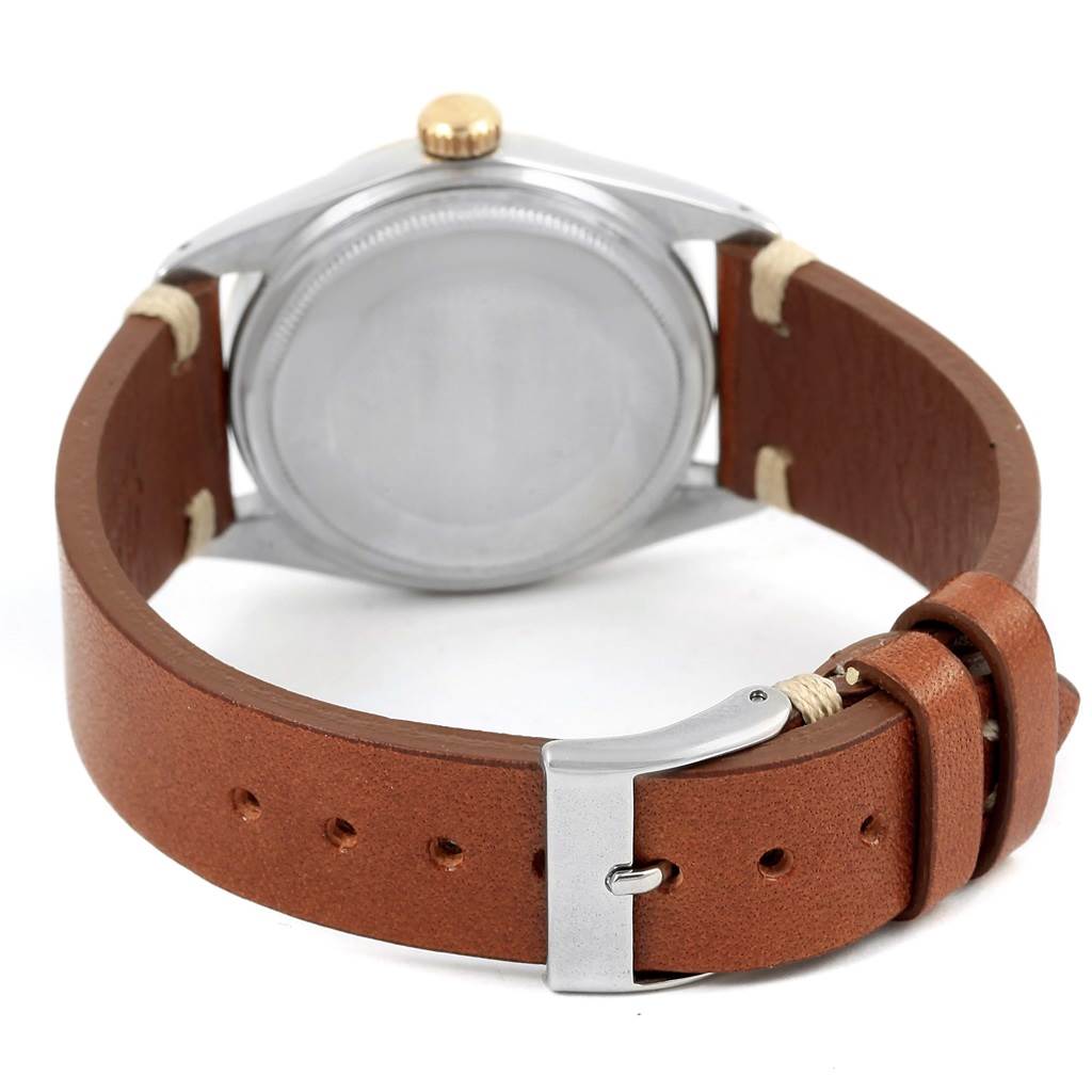 The image shows the back view of a Rolex Vintage Collection 1601 Men's Steel and Gold (two tone) Champagne Dial 1601 Men's Steel and Gold (two tone) Champagne Dial watch with a brown leather strap and a silver buckle.