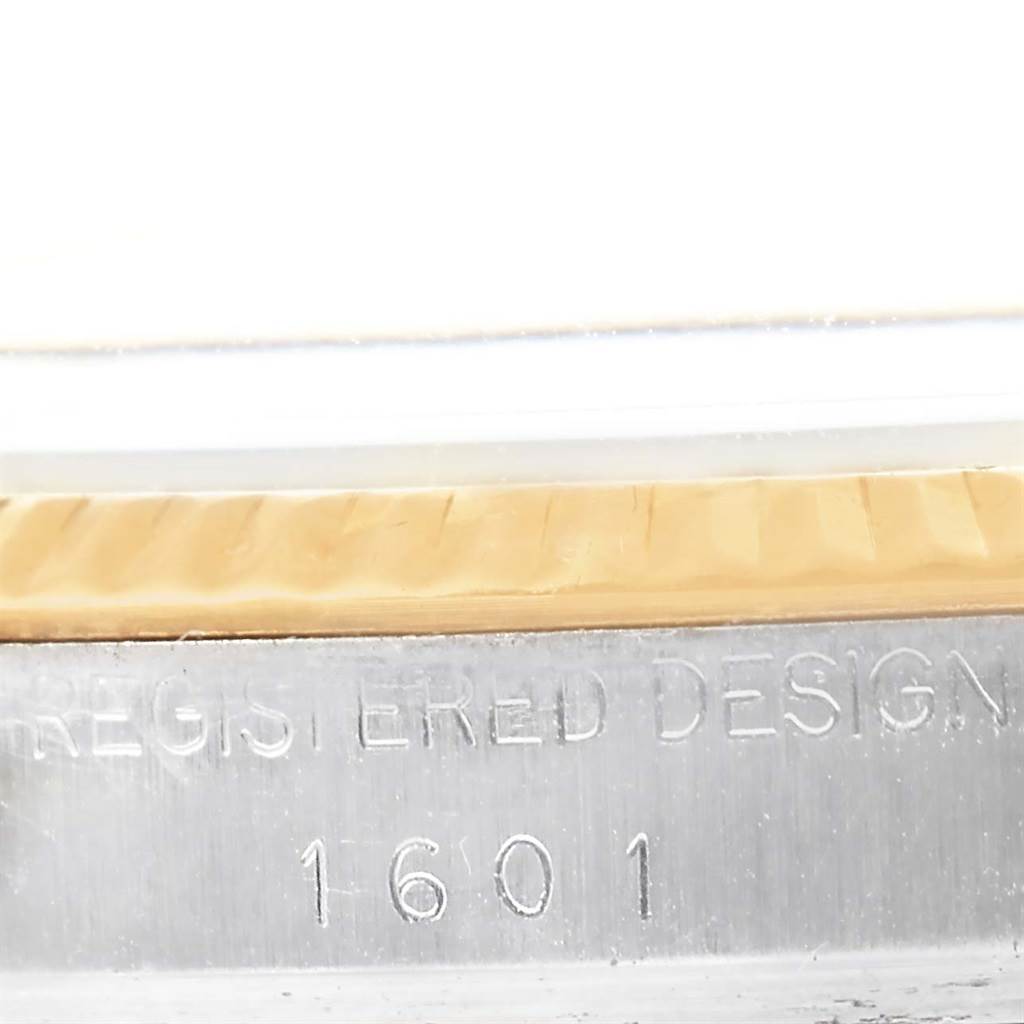 The image shows a close-up of the side of the Rolex Vintage Collection 1601 Men's Steel and Gold (two tone) Grey Dial 1601 Men's Steel and Gold (two tone) Grey Dial model, highlighting its etched text and a part of the bezel.