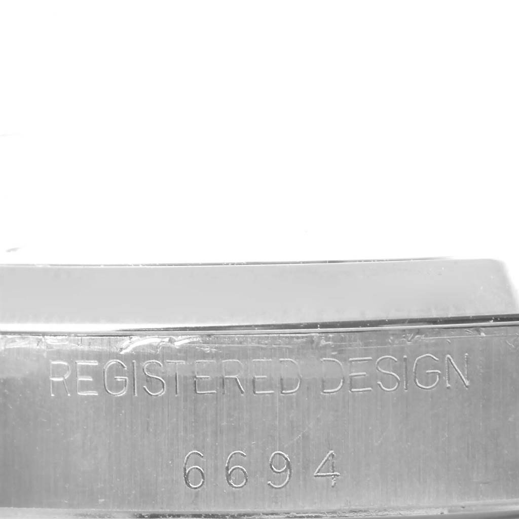 The image shows a close-up of the side of the case from the Rolex Vintage Collection 6694 Men's Stainless Steel Blue Dial 6694 Men's Stainless Steel Blue Dial model with the engraving "REGISTERED DESIGN 6694."