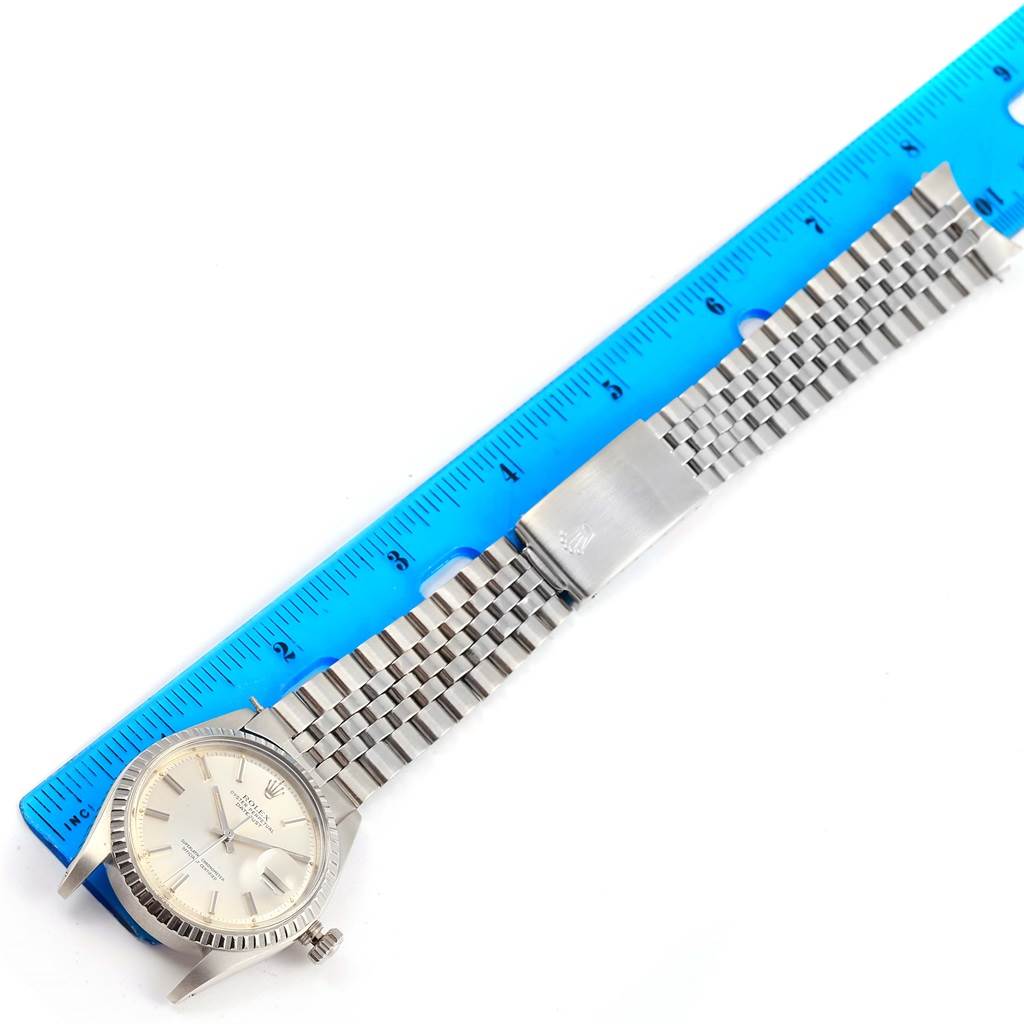 The image shows the top view of a Rolex Vintage Collection 1603 Men's Stainless Steel Silver Dial 1603 Men's Stainless Steel Silver Dial watch with a stainless steel bracelet, next to a blue ruler.