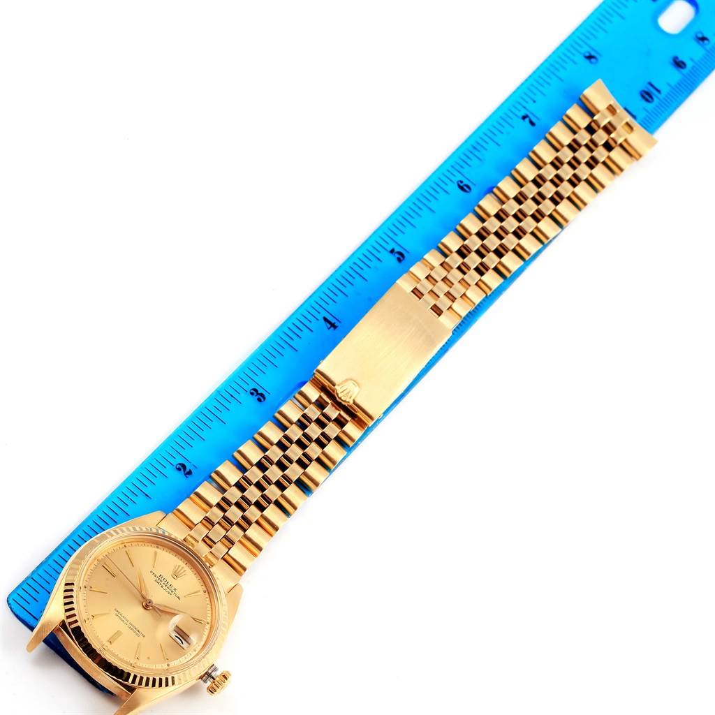 The image shows a Rolex Vintage Collection 1601 Men's Yellow Gold Champagne Dial 1601 Men's Yellow Gold Champagne Dial watch laid flat next to a blue ruler, displaying its face and gold bracelet.