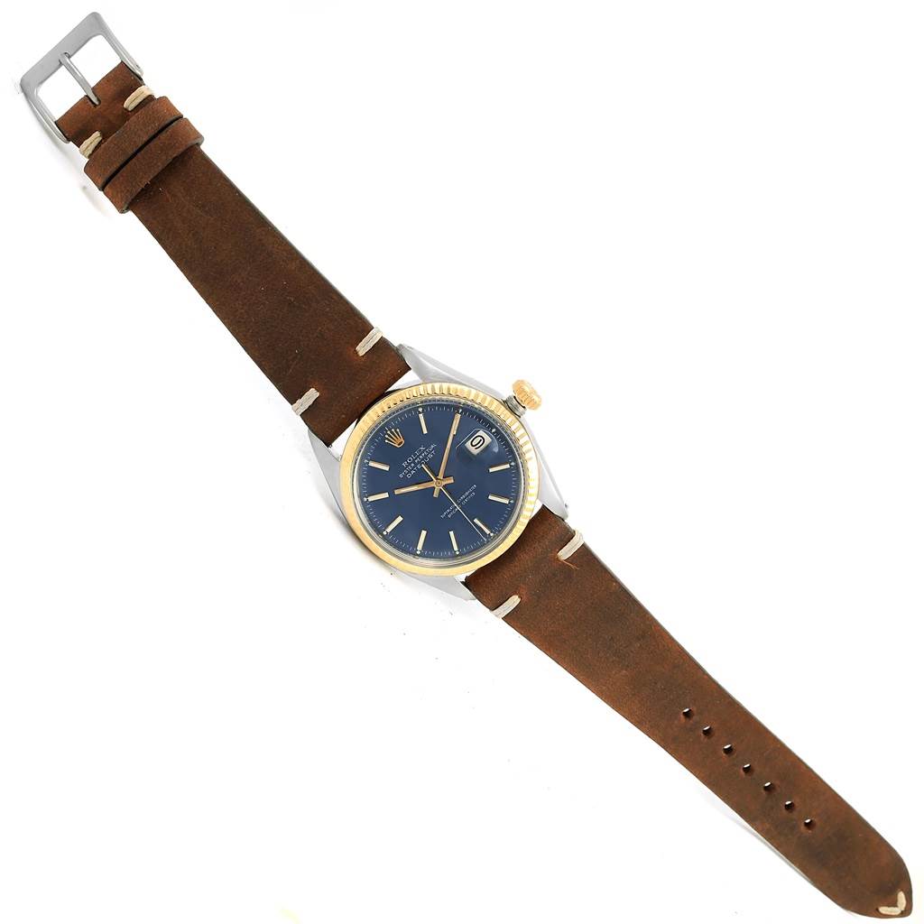 The Rolex Vintage Collection 1601 Men's Steel and Gold (two tone) Blue Dial 1601 Men's Steel and Gold (two tone) Blue Dial watch is shown from a top-down angle, displaying its brown leather strap, gold bezel, blue dial, and date window.