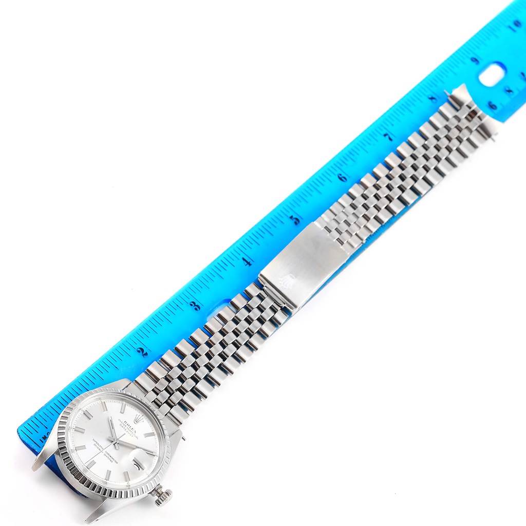 This image shows the Rolex Vintage Collection 1603 Men's Stainless Steel Silver Dial 1603 Men's Stainless Steel Silver Dial watch laid flat next to a blue ruler, displaying the watch face and metal strap.