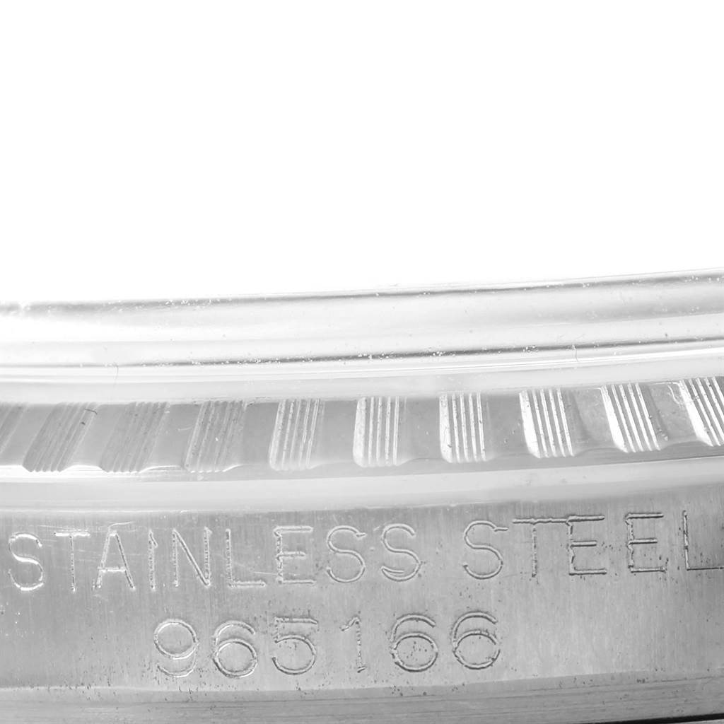 This image shows a close-up of the side of a Rolex Vintage Collection 1603 Men's Stainless Steel Silver Dial 1603 Men's Stainless Steel Silver Dial model watch, featuring its engraved serial number and fluted bezel.