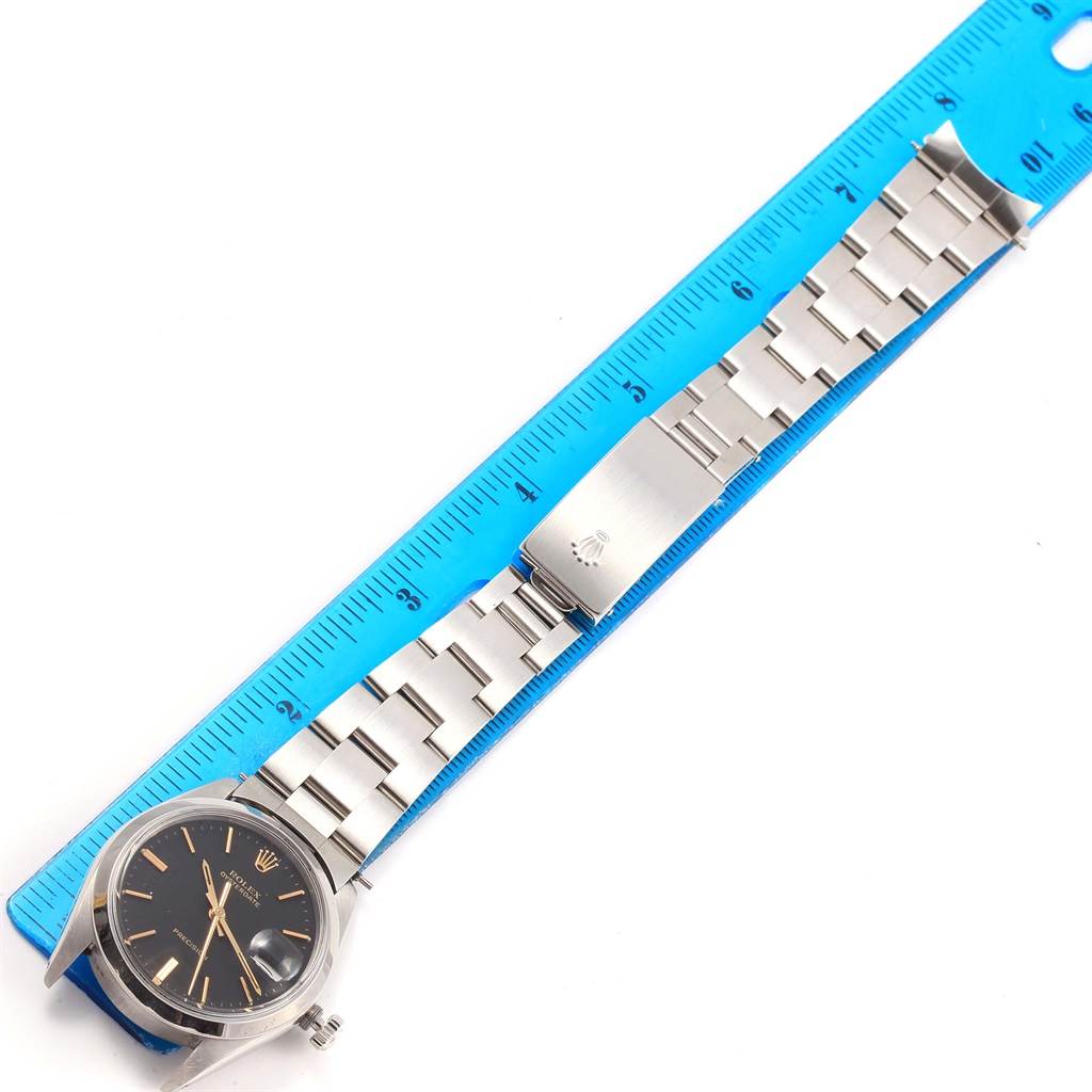 The Vintage Collection by Rolex is shown flat with its silver bracelet on a blue ruler for reference.