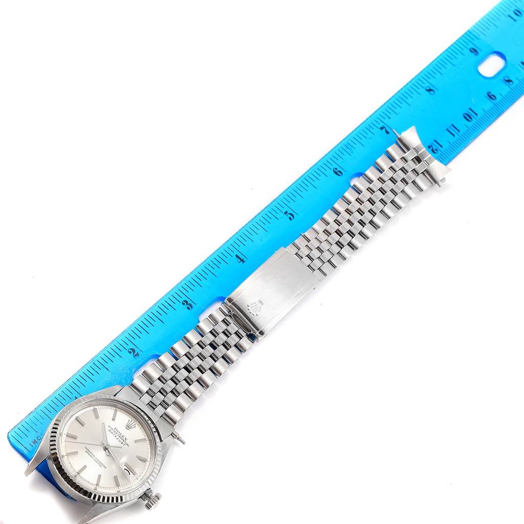 The Rolex Vintage Collection 1601 Men's Stainless Steel Silver Dial 1601 Men's Stainless Steel Silver Dial watch is shown from an overhead angle, displaying the face, bracelet, and clasp beside a ruler.