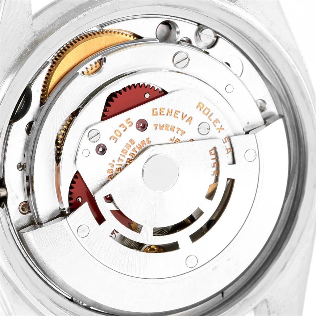 The image shows the internal mechanism of the Vintage Collection Rolex model, viewed from the back with gears and engravings visible.