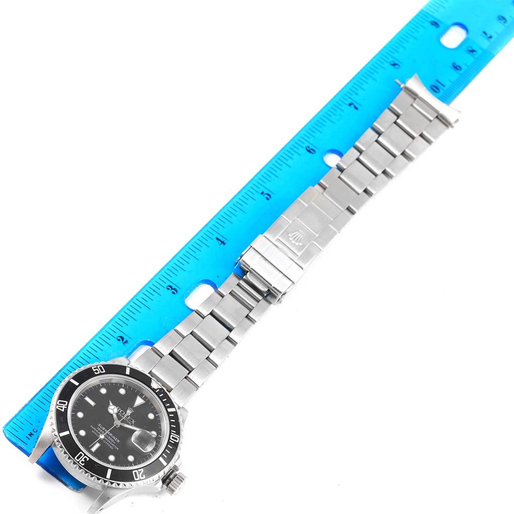 The image shows a flat lay of a Rolex Vintage Collection 16800 Men's Stainless Steel Black Dial 16800 Men's Stainless Steel Black Dial watch, displaying the watch face and metal strap, measured against a blue ruler.