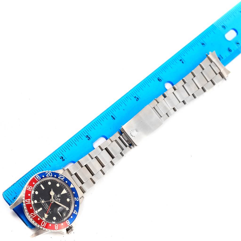 The image shows a top-down view of a Vintage Collection Rolex watch with a metal bracelet next to a blue ruler.