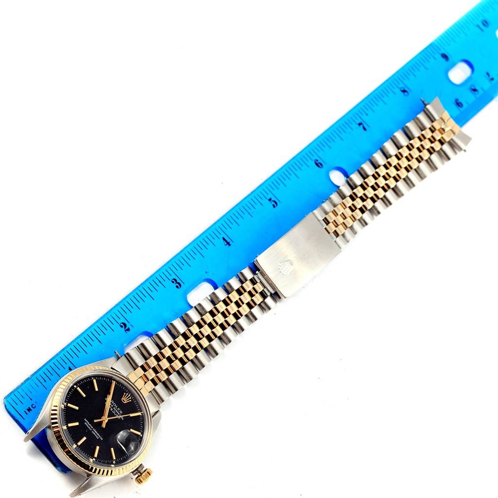 The Rolex Vintage Collection 1600 Men's Stainless Steel Black Dial 1600 Men's Stainless Steel Black Dial watch is shown from a top view, featuring its face, band, and clasp alongside a blue ruler.