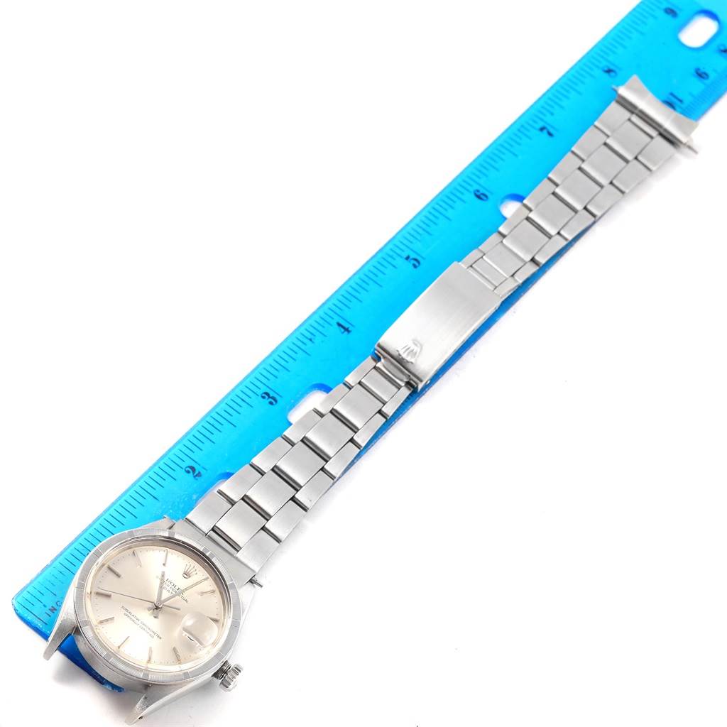 This image shows a Rolex Vintage Collection 1501 Men's Stainless Steel Silver Dial 1501 Men's Stainless Steel Silver Dial watch placed flat with its dial face up next to a blue ruler.