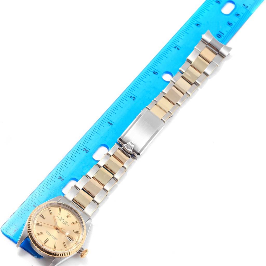 The image shows a Rolex Vintage Collection 1603 Men's Steel and Gold (two tone) Champagne Dial 1603 Men's Steel and Gold (two tone) Champagne Dial watch laid flat next to a ruler, displaying its face, bracelet, and clasp.