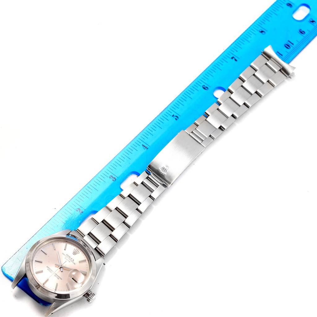 The Rolex Vintage Collection 1501 Men's Stainless Steel Silver Dial 1501 Men's Stainless Steel Silver Dial model watch is shown from a top angle, displaying the face, band, and clasp beside a blue ruler.