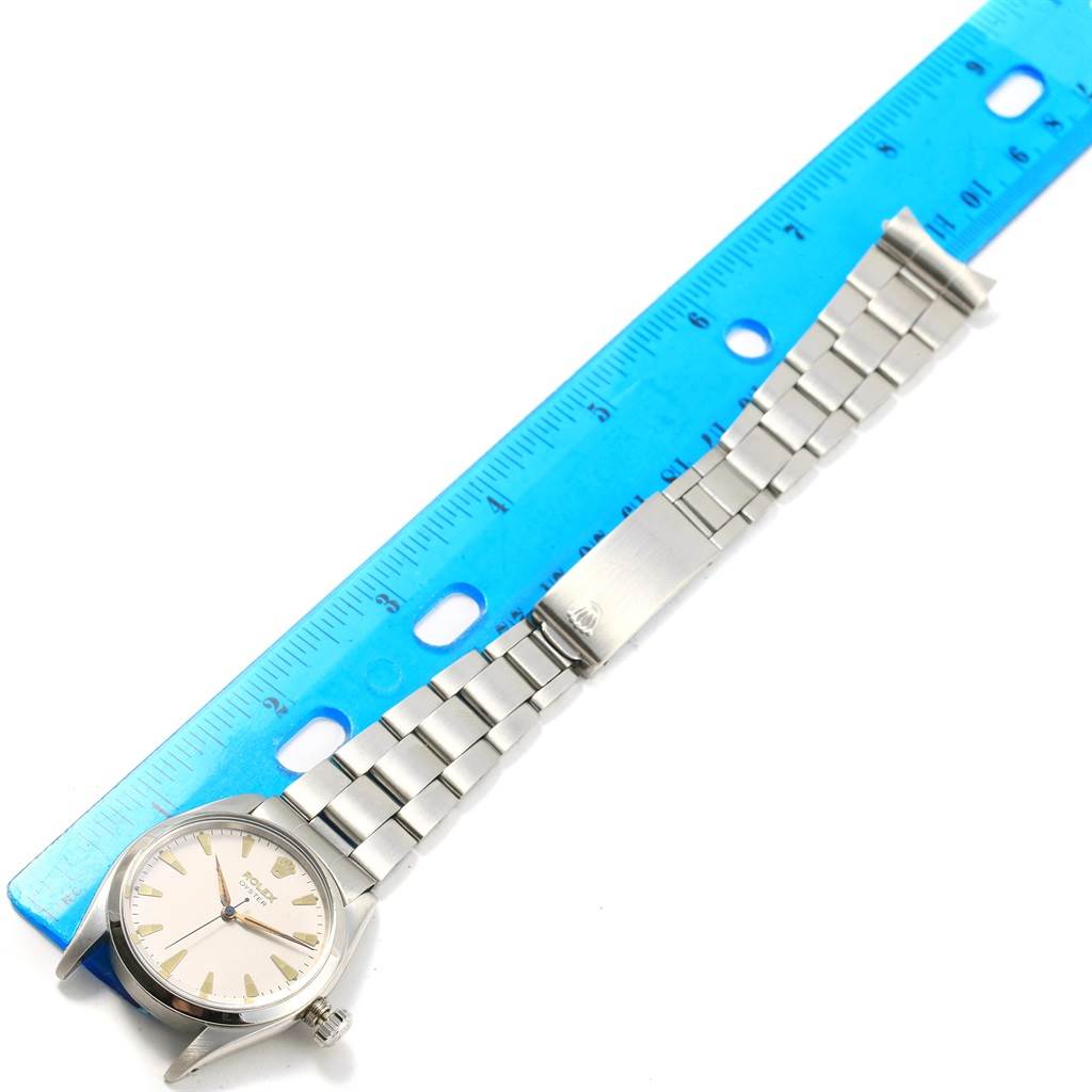 The image shows a flat-lay of a Vintage Collection Rolex watch with its clasp open next to a blue ruler for size reference.