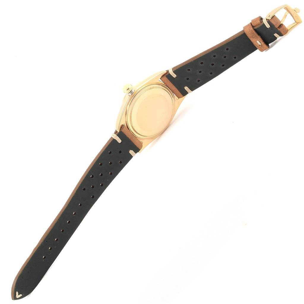 The image shows the back view of the Rolex Vintage Collection 1807 Men's Yellow Gold Champagne Dial 1807 Men's Yellow Gold Champagne Dial model, including its case and black perforated strap.