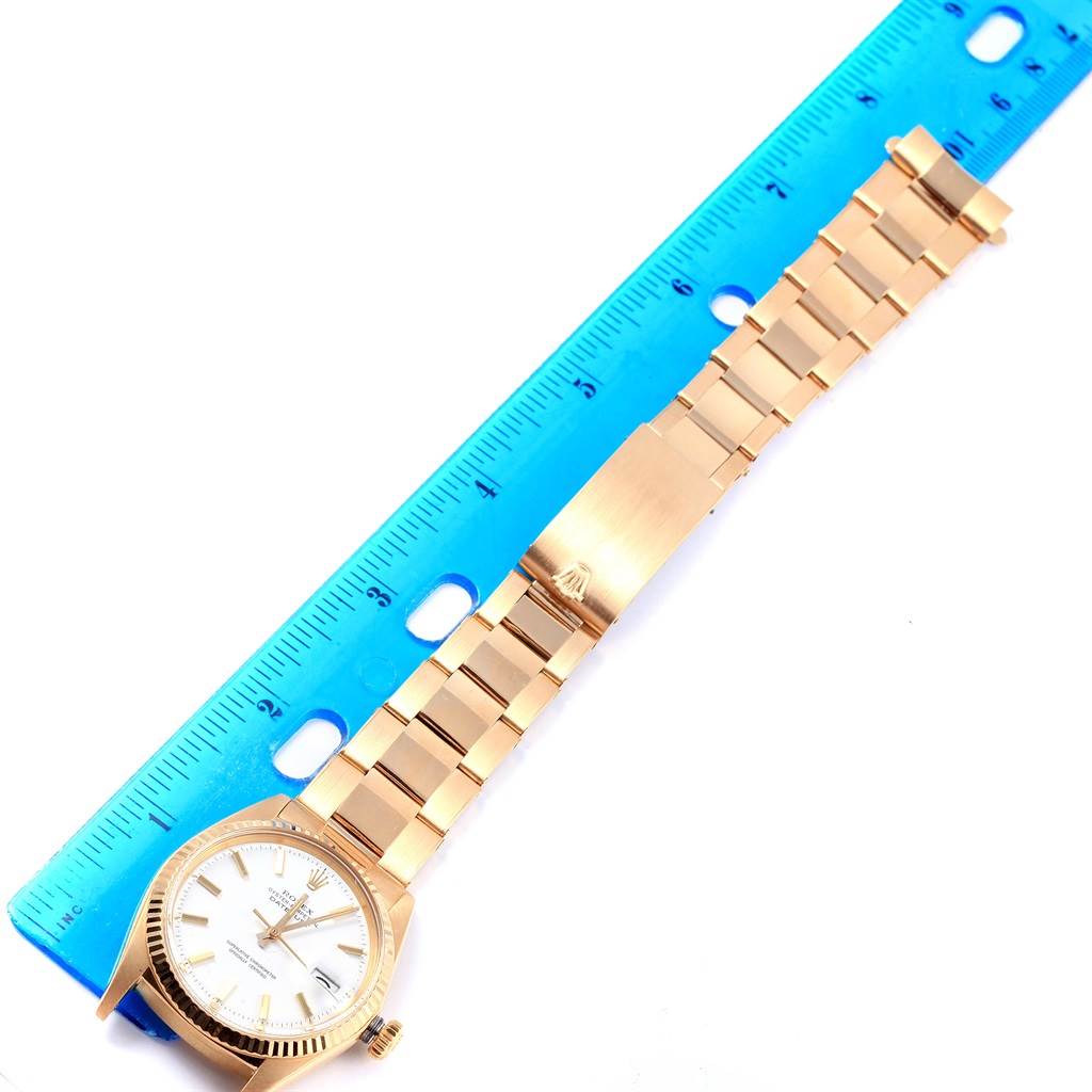 This image shows a Rolex Vintage Collection 1601 Men's Yellow Gold White Dial 1601 Men's Yellow Gold White Dial watch laid flat next to a blue ruler.