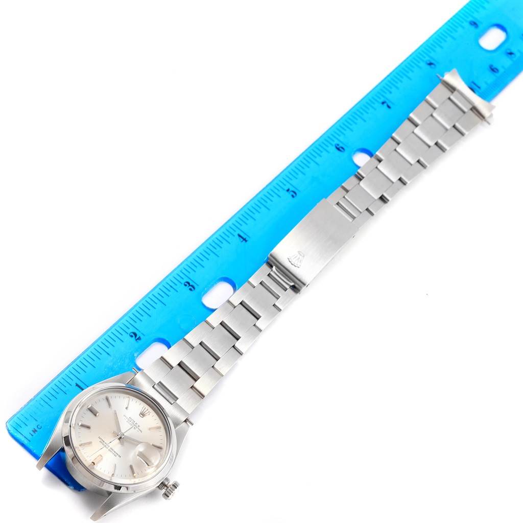 The Rolex Vintage Collection 1500 Men's Stainless Steel Silver Dial 1500 Men's Stainless Steel Silver Dial watch is shown flat with its stainless steel band stretched alongside a blue ruler for measurement.