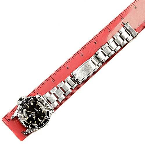 The image shows the Rolex Vintage Collection 5513 Men's Stainless Steel Black Dial 5513 Men's Stainless Steel Black Dial model overhead with a metal bracelet and clasp, aligned with a red measuring ruler.