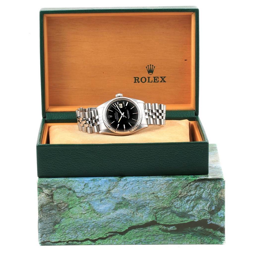 The image shows a Rolex Vintage Collection 1601 Men's Stainless Steel Black Dial 1601 Men's Stainless Steel Black Dial watch placed at an angle inside its open green and orange box.