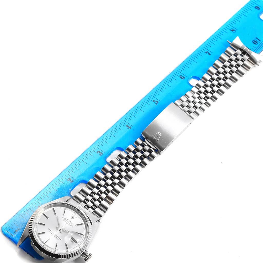 The image shows a partial view of a Rolex Vintage Collection 1601 Men's Stainless Steel Silver Dial 1601 Men's Stainless Steel Silver Dial watch with its face, crown, and band aligned next to a ruler.