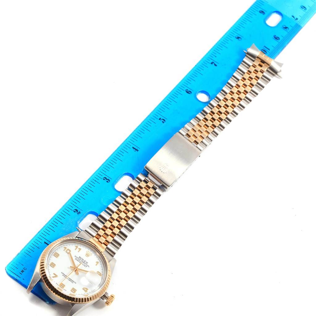 This image shows a Vintage Collection Rolex watch placed next to a blue ruler, displaying its face, crown, and metal bracelet.