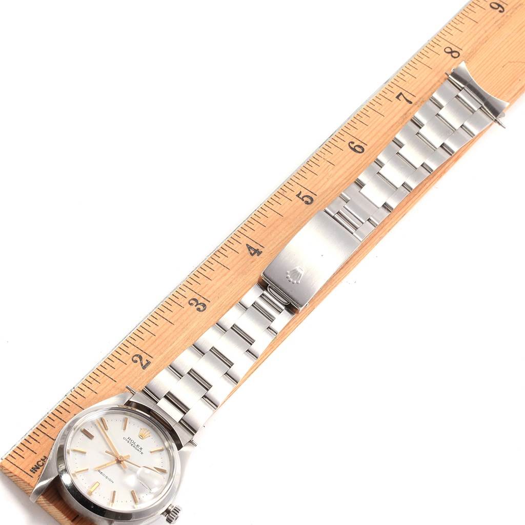 The image shows a Rolex Vintage Collection 6694 Men's Stainless Steel White Dial 6694 Men's Stainless Steel White Dial watch laying flat, with its full bracelet and clasp, alongside a wooden ruler.