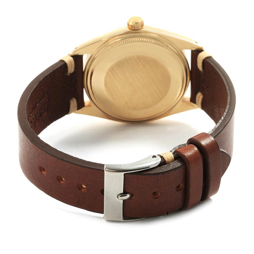 The image shows the back view of a Rolex Vintage Collection 1500 Men's Yellow Gold Silver Dial 1500 Men's Yellow Gold Silver Dial watch, highlighting its case back and brown leather strap with buckle.