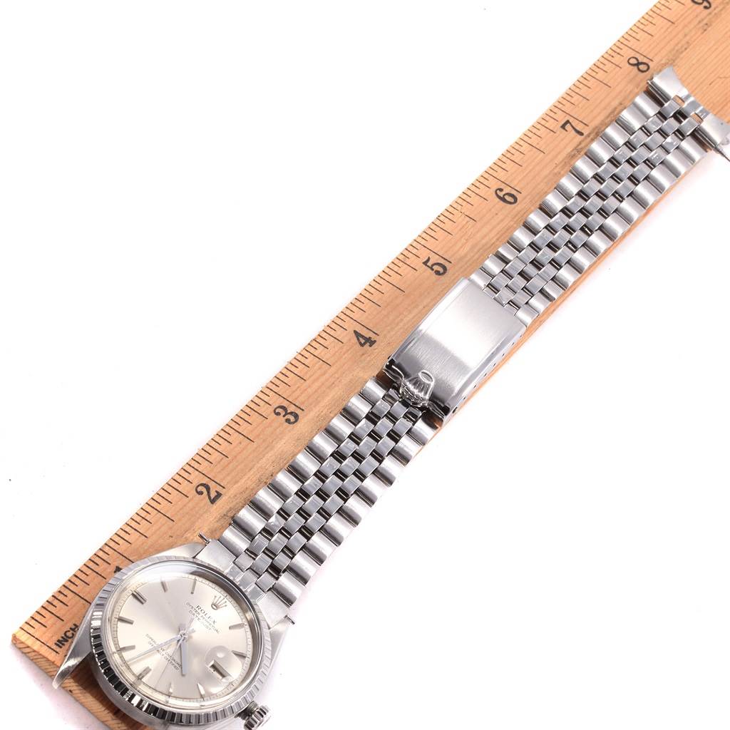 The image shows a Rolex Vintage Collection 1601 Men's Stainless Steel Silver Dial 1601 Men's Stainless Steel Silver Dial watch laying flat beside a ruler, displaying its face and metallic bracelet.