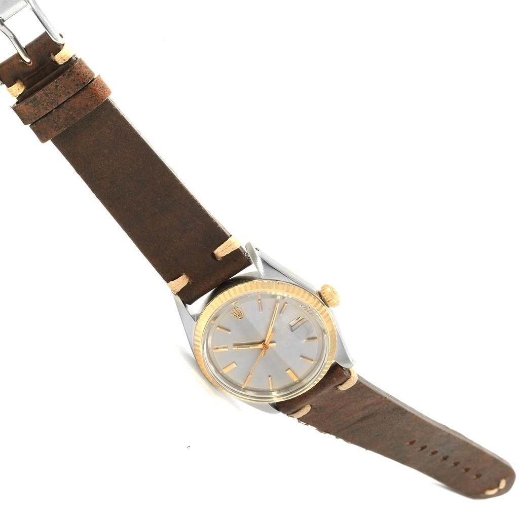 The image shows a side and partial top view of a Rolex Vintage Collection 1601 Men's Steel and Gold (two tone) Grey Dial 1601 Men's Steel and Gold (two tone) Grey Dial watch with a brown leather strap and a gold-tone bezel.