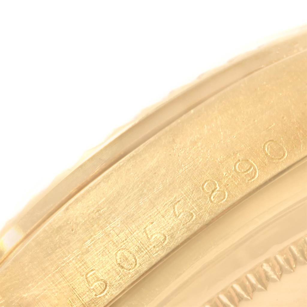 The image shows a close-up of the edge of a Rolex Vintage Collection 1803 Men's Yellow Gold Silver Dial 1803 Men's Yellow Gold Silver Dial model watch, featuring a portion of its gold casing and engraved serial number.