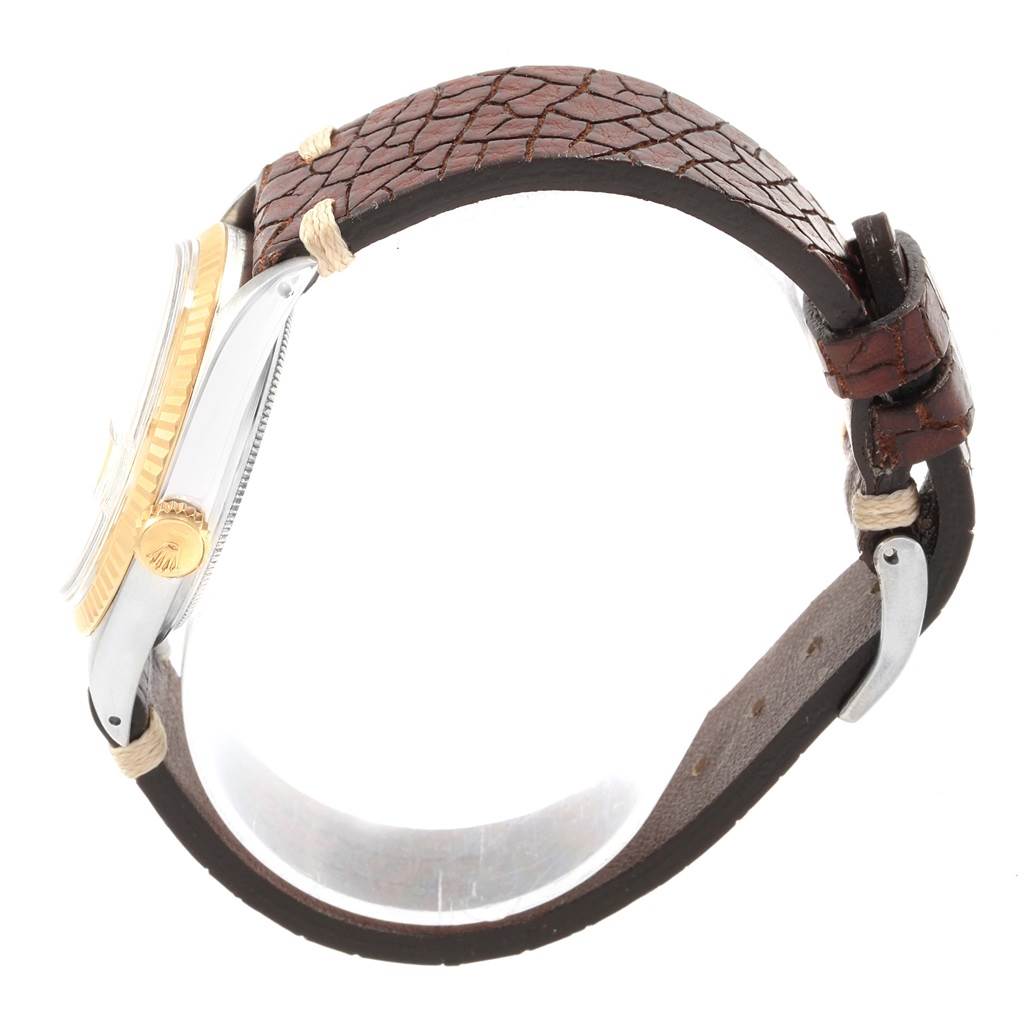 This side view of the Rolex Vintage Collection 1601 Men's Steel and Gold (two tone) Champagne Dial 1601 Men's Steel and Gold (two tone) Champagne Dial watch shows its brown leather strap and gold-accented case with the crown visible.