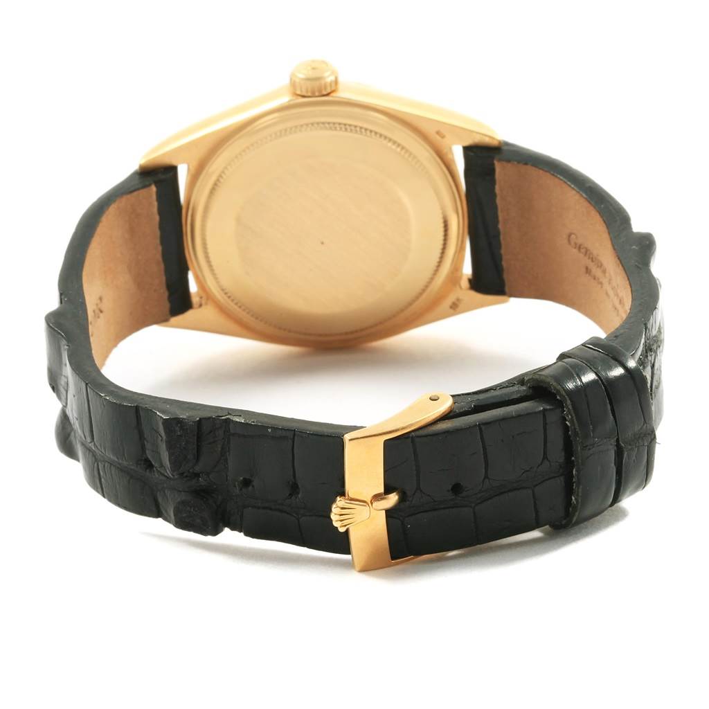 The image shows the back of a Rolex Vintage Collection 1803 Men
s Yellow Gold Black Dial 1803 Men
s Yellow Gold Black Dial watch, highlighting its gold case and black leather strap with a gold clasp.