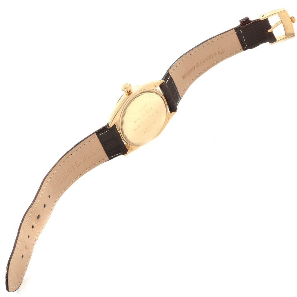 This image shows the back view of a Rolex Vintage Collection 1002 Men's Yellow Gold Silver Dial 1002 Men's Yellow Gold Silver Dial watch, highlighting its case back, crown, and leather strap.