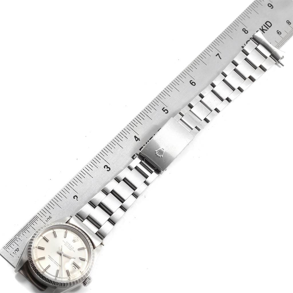 The image shows a Rolex Vintage Collection 1603 Men
s Stainless Steel Silver Dial 1603 Men
s Stainless Steel Silver Dial watch with a full view of the bracelet and clasp, alongside a ruler for scale.