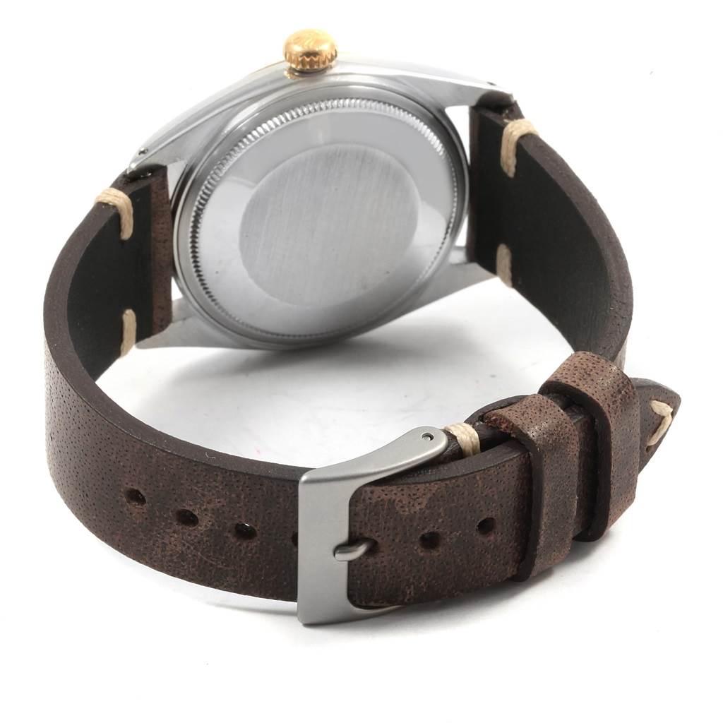 The image shows the back and side view of the Rolex Vintage Collection 1601 Men
s Steel and Gold (two tone) Champagne Dial 1601 Men
s Steel and Gold (two tone) Champagne Dial watch with a brown leather strap and silver clasp.