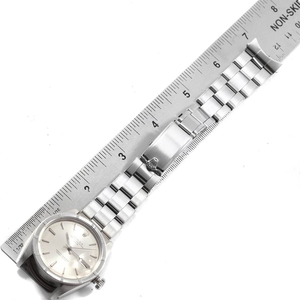 The image shows a Rolex Vintage Collection 1501 Men
s Stainless Steel Silver Dial 1501 Men
s Stainless Steel Silver Dial watch laid flat next to a ruler, displaying the watch
s face, band, and clasp.