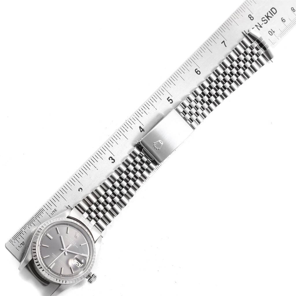 The image shows a Rolex Vintage Collection 1603 Men
s Stainless Steel Grey Dial 1603 Men
s Stainless Steel Grey Dial watch laid flat, with a stainless steel bracelet and clasp, alongside a ruler for measurement.