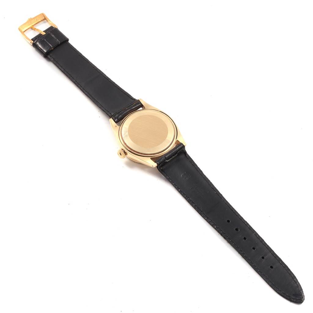 The Rolex Vintage Collection 1003 Men's Yellow Gold Silver Dial 1003 Men's Yellow Gold Silver Dial watch is shown from the back, displaying its leather strap, gold case, and closed case back.