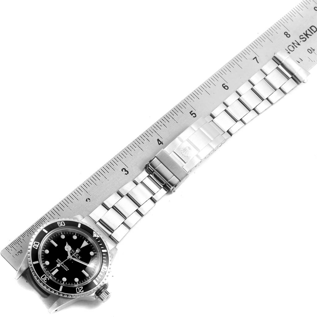 The image shows the Rolex Vintage Collection 5513 Men
s Stainless Steel Black Dial 5513 Men
s Stainless Steel Black Dial watch laid flat next to a ruler, highlighting its band length and face.