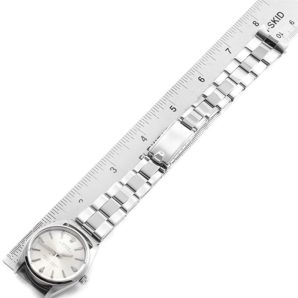 The image shows a flat-lay angle of a Rolex Vintage Collection 1002 Men's Stainless Steel Silver Dial 1002 Men's Stainless Steel Silver Dial watch, highlighting its face, bracelet, and clasp alongside a ruler.