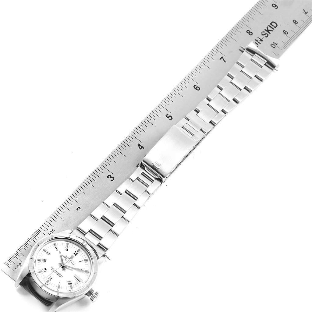 This image shows the Rolex Vintage Collection 1501 Men
s Stainless Steel White Dial 1501 Men
s Stainless Steel White Dial watch laid flat, with a close-up on its face and metal band, alongside a ruler for scale.