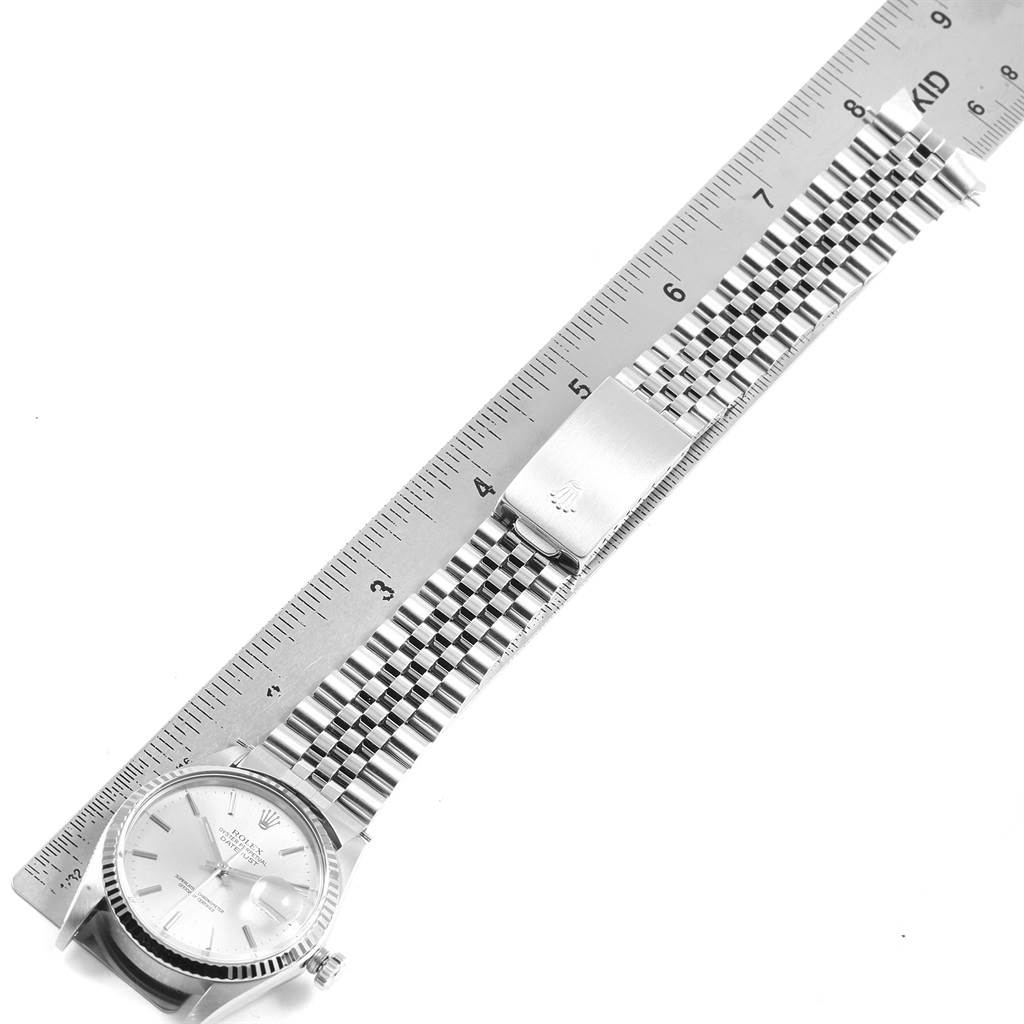 This image shows the side angle of a Rolex Vintage Collection 16014 Men's Stainless Steel Silver Dial 16014 Men's Stainless Steel Silver Dial watch with its face, bracelet, and clasp, alongside a measuring ruler.