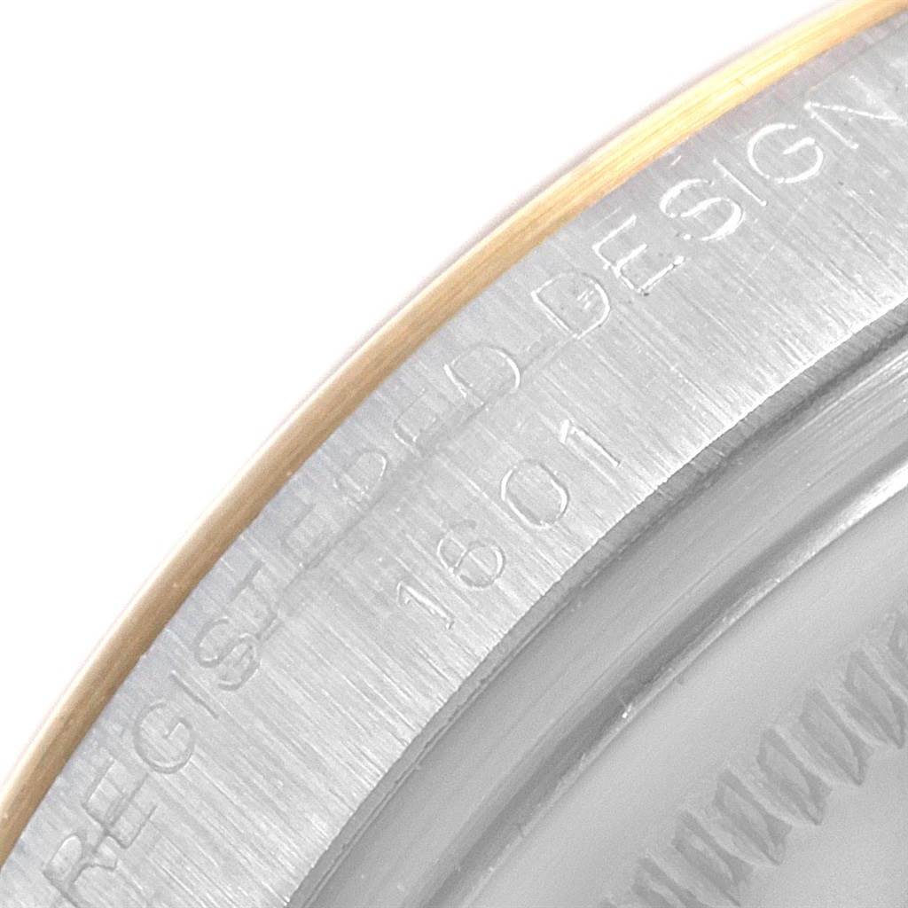 This image shows a close-up of the edge of a Rolex Vintage Collection 1601 Men
s Steel and Gold (two tone) Grey Dial 1601 Men
s Steel and Gold (two tone) Grey Dial watch, featuring part of the bezel and engraved design details.