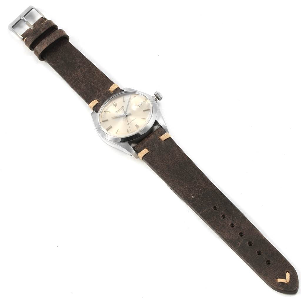 The image shows a Rolex Vintage Collection 6694 Men
s Stainless Steel Silver Dial 6694 Men
s Stainless Steel Silver Dial watch from an angled top-down view, highlighting the face, case, crown, and leather strap.