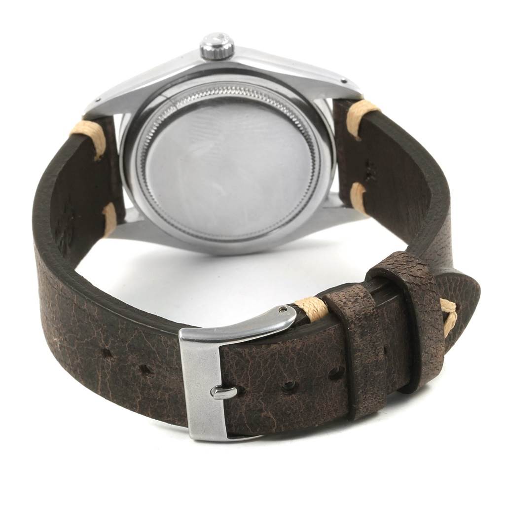 The image shows the back of a Rolex Vintage Collection 6694 Men
s Stainless Steel Silver Dial 6694 Men
s Stainless Steel Silver Dial watch, highlighting its caseback, crown, and leather strap with a buckle.